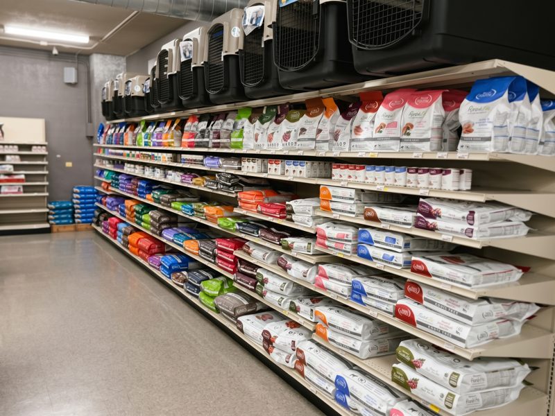An aisle of cat litter and cat food bags stacked to the top shelf